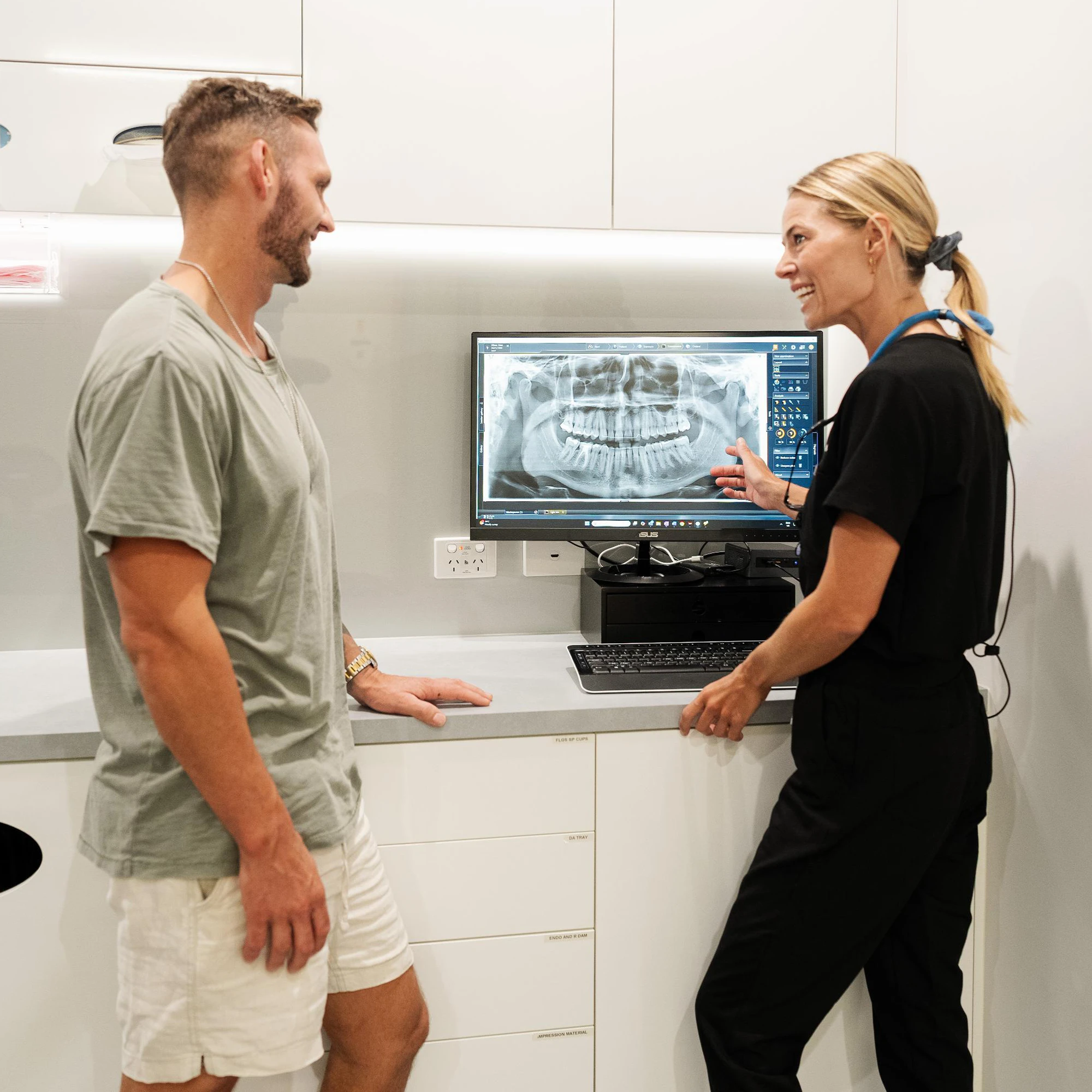 Patient asking dental implant questions while reviewing a dental X-ray with a dentist